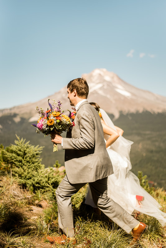 bride and groom walk in front of Mt. Hood on their wedding day