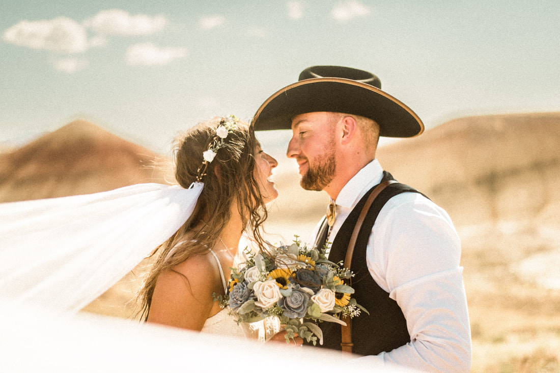 bride and groom look at each other while taking photos in the painted hills of oregon